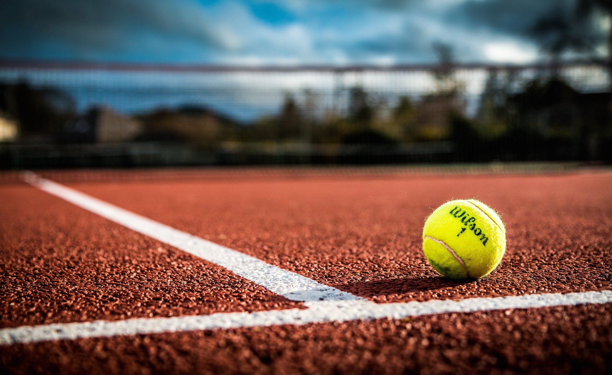 A tennis ball is laying on the ground.