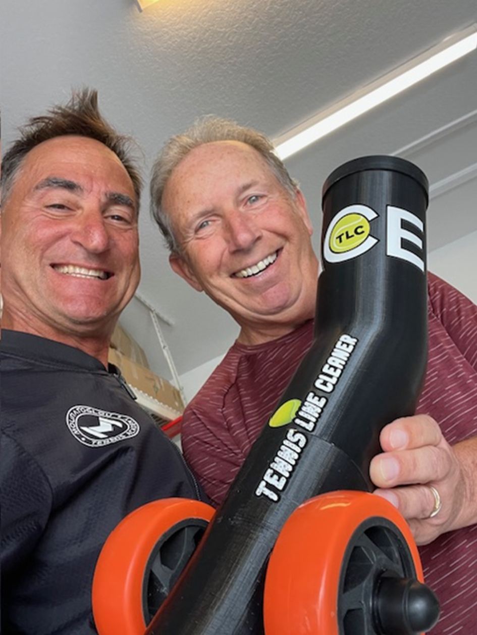 Two men holding a large tennis racket.